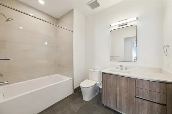 a bathroom with a bathtub shower sink vanity and toilet