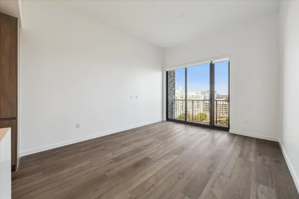 a view of an empty room with wooden floor and a window