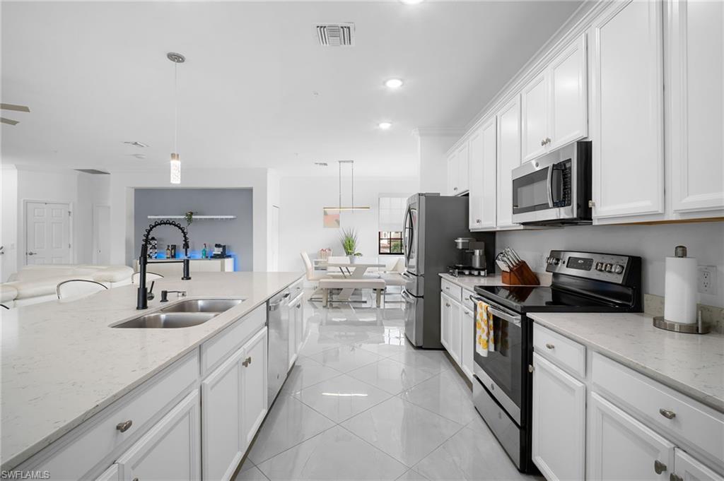11879 Arboretum Run Drive, Unit 201 Fort Myers, FL 33913 - Photo 12 of 37 Kitchen featuring appliances with stainless steel finishes, hanging light fixtures, white cabinetry, light stone counters, and recessed lighting