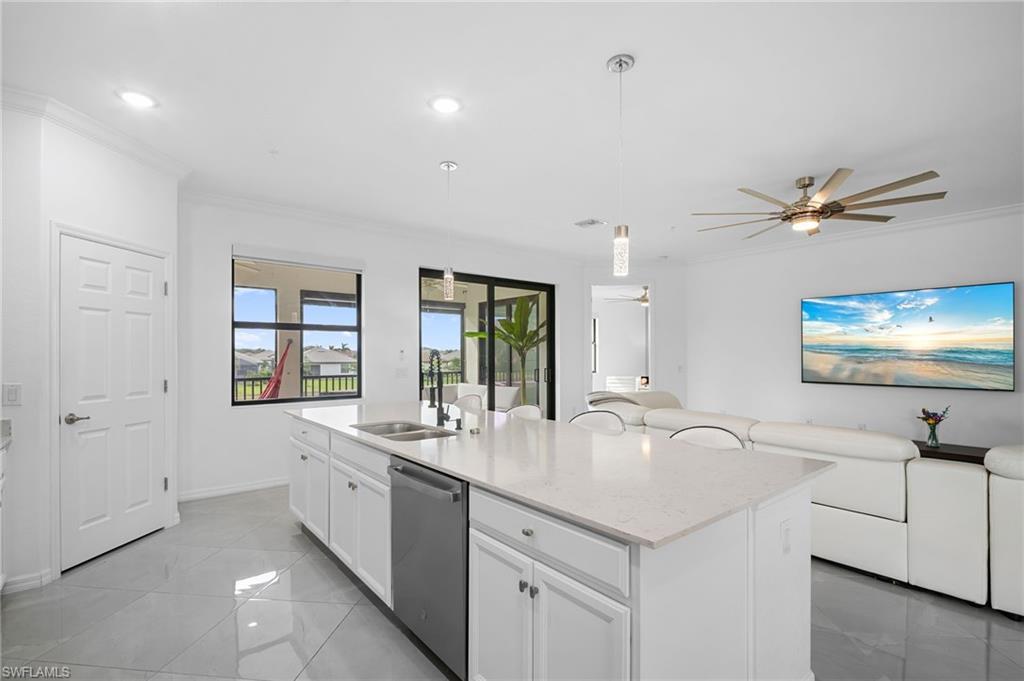 11879 Arboretum Run Drive, Unit 201 Fort Myers, FL 33913 - Photo 14 of 37 Kitchen with white cabinetry, pendant lighting, ornamental molding, light stone countertops, and dishwasher