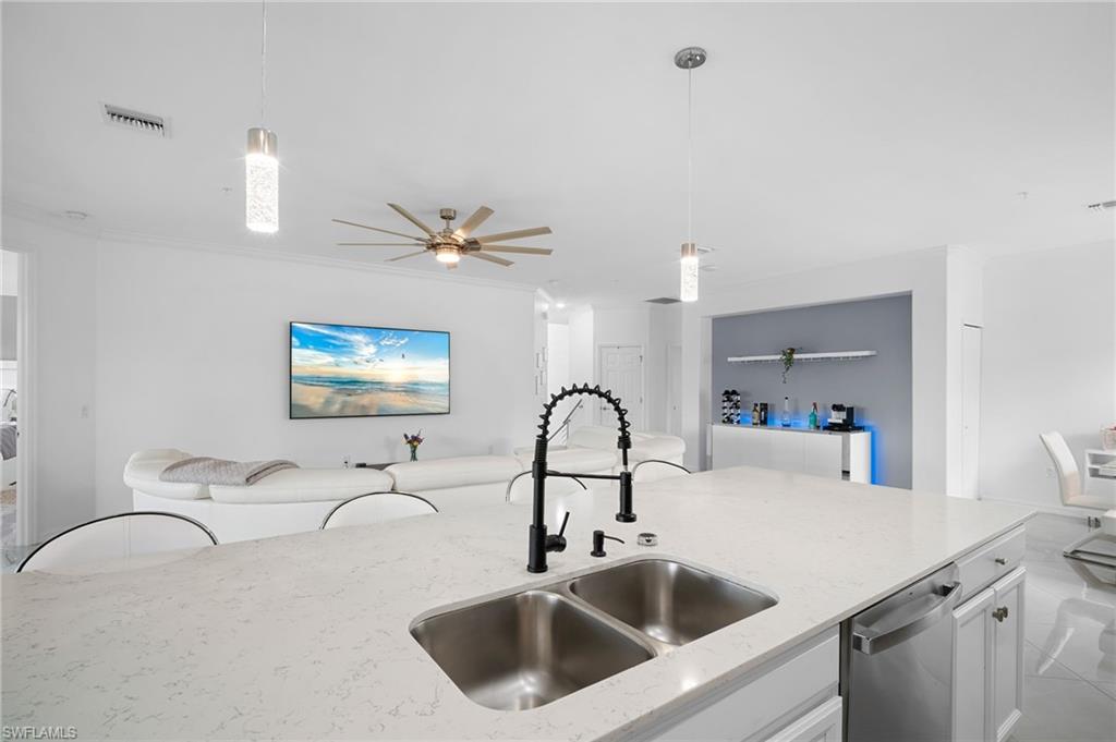 11879 Arboretum Run Drive, Unit 201 Fort Myers, FL 33913 - Photo 16 of 37 Kitchen featuring white cabinets, decorative light fixtures, open floor plan, light stone counters, and stainless steel dishwasher