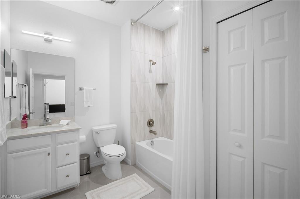 11879 Arboretum Run Drive, Unit 201 Fort Myers, FL 33913 - Photo 31 of 37 Bathroom featuring shower / bath combo with shower curtain, vanity, a closet, and light tile patterned flooring