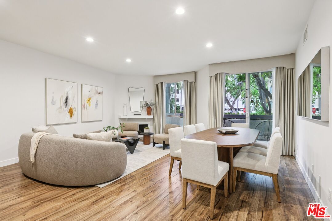 a living room with furniture a large window and wooden floor