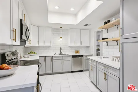 a kitchen with stainless steel appliances granite countertop a sink dishwasher stove refrigerator and cabinets