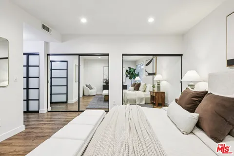 a bedroom with a large bed and wooden floor