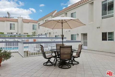 a view of a patio with a table and chairs under an umbrella