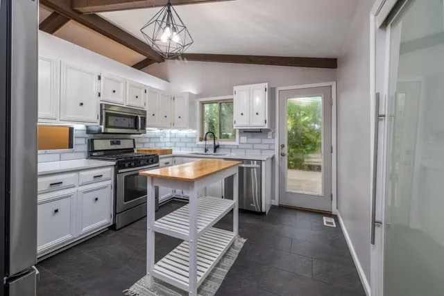 a kitchen with granite countertop a sink appliances cabinets and a counter top space