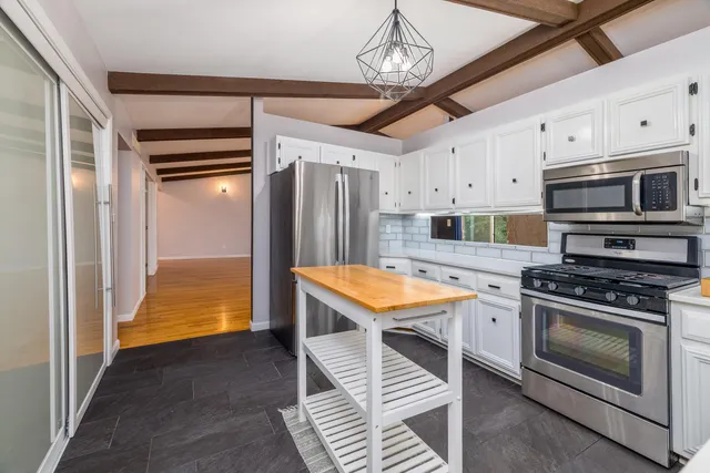 a kitchen with stainless steel appliances granite countertop a stove a refrigerator and a microwave