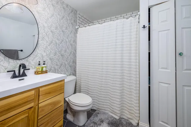 a bathroom with a toilet sink vanity and mirror