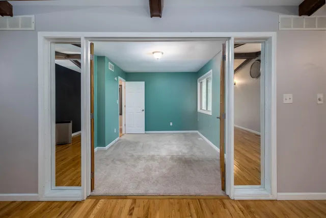 a view of a hallway with wooden floor and closet