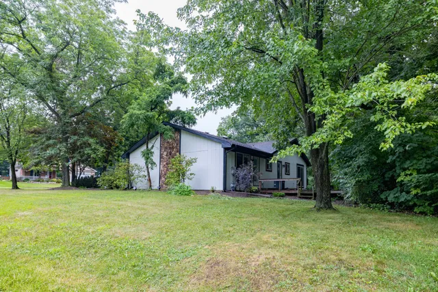 a view of a house with a yard and large trees