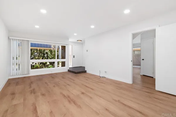 a view of an empty room with a window and wooden floor