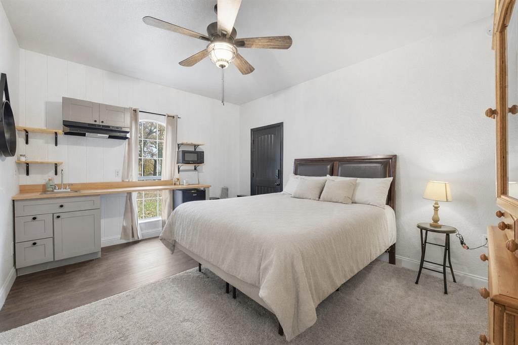 156 Howard Newby Lane Springtown, TX 76082 - Photo 3 of 11 a bedroom with a large bed and a chandelier fan