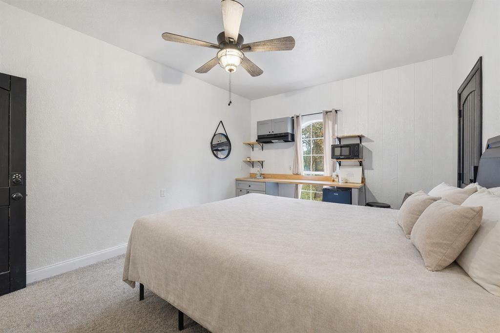 156 Howard Newby Lane Springtown, TX 76082 - Photo 7 of 11 a bedroom with a large bed and a chandelier