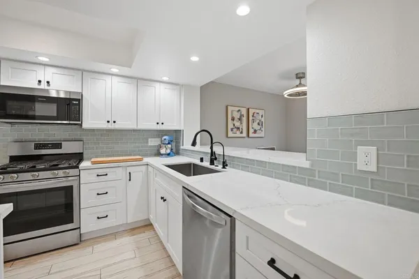a kitchen with white cabinets and appliances