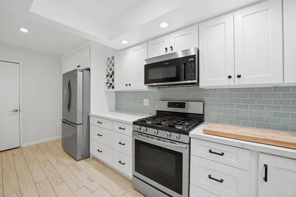 a kitchen with stainless steel appliances white cabinets a stove a microwave and a refrigerator