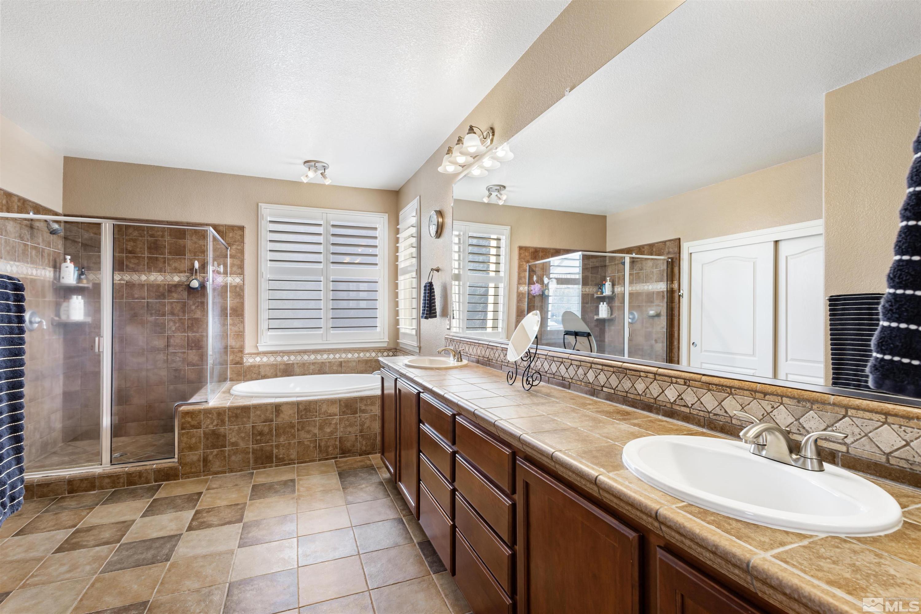 14025 Tagor Road Reno, NV 89521 - Photo 22 of 39 a spacious bathroom with a granite countertop sink a mirror and a bathtub