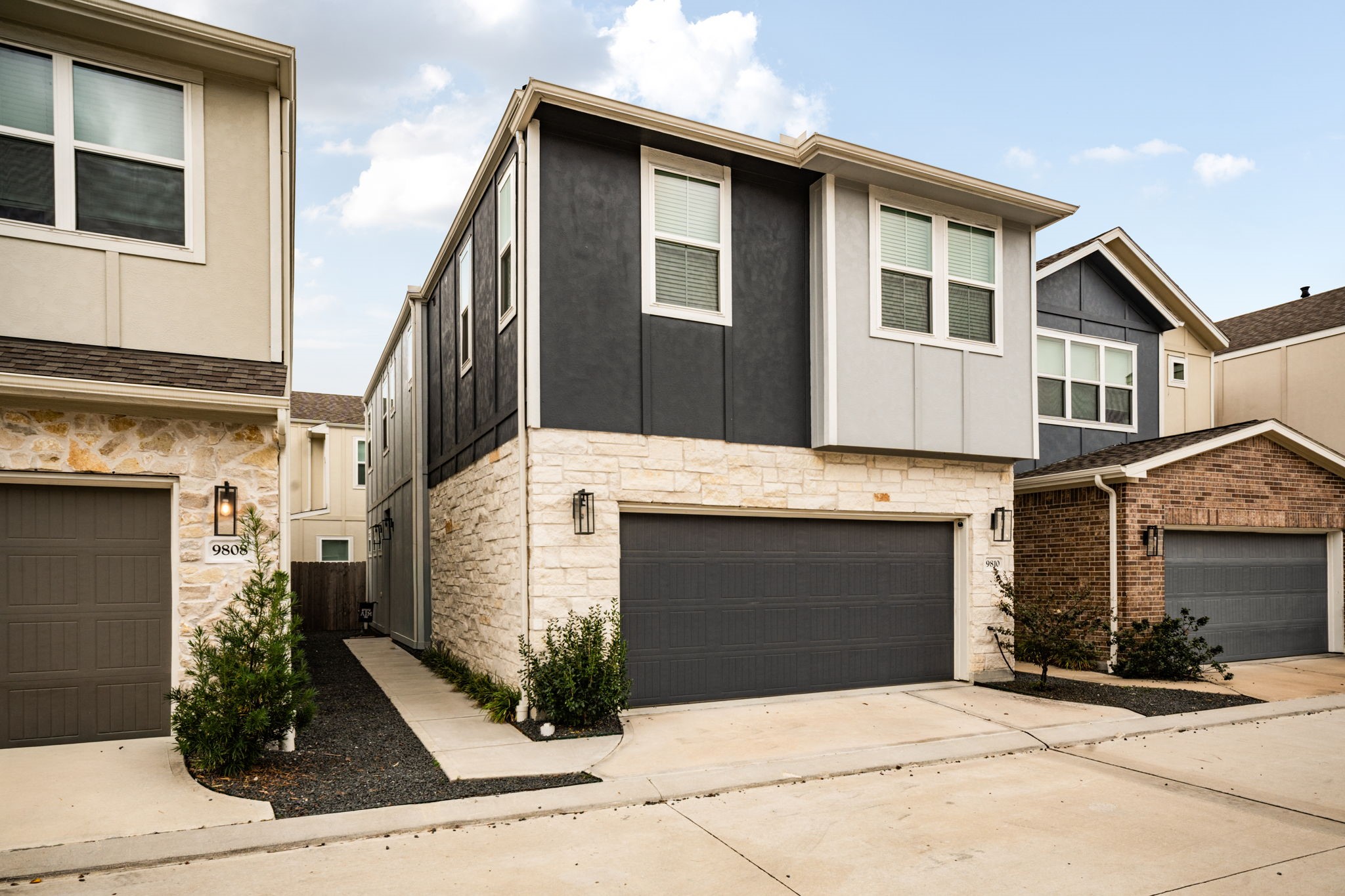 9810 Falling Fern Lane Houston, TX 77080 - Photo 3 of 30 Striking modern exterior with a sleek two-tone facade, stone accents, and contemporary lighting. The home features a wide two-car garage, low-maintenance landscaping, and a private side walkway leading to the main entrance.