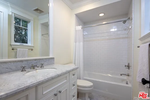 a bathroom with a granite countertop sink toilet and mirror