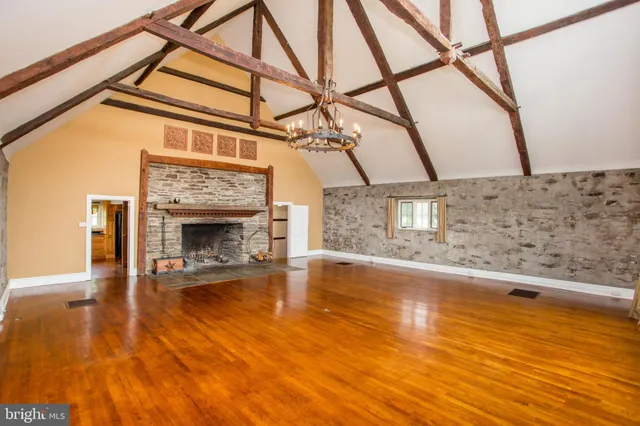 a view of an empty room with a fireplace and wooden floor