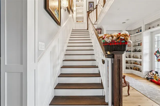 a view of staircase with lots of frames on wall and wooden floor