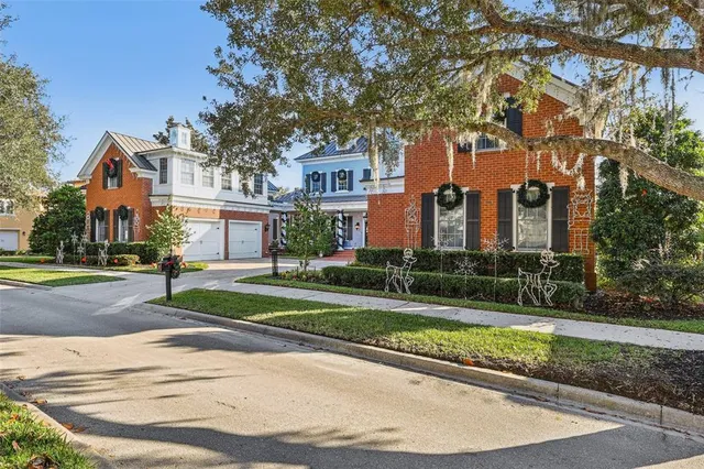 a view of a white house next to a yard with large trees