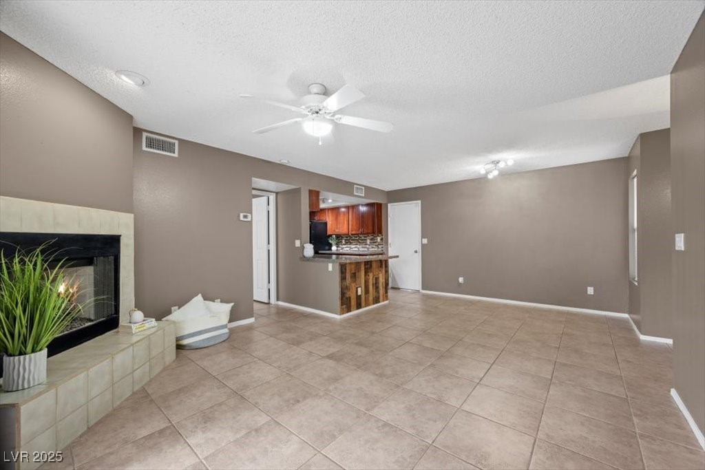 2995 East Sunset Road, Unit 134 Las Vegas, NV 89120 - Photo 3 of 20 Spacious living area with ceiling fan & lighting, 18" light tile patterned floors, tiled fireplace