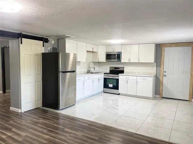 a kitchen with a refrigerator a stove top oven and white kitchen