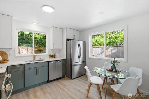 a kitchen with stainless steel appliances granite countertop a refrigerator a sink dishwasher a stove and white countertops with wooden floor