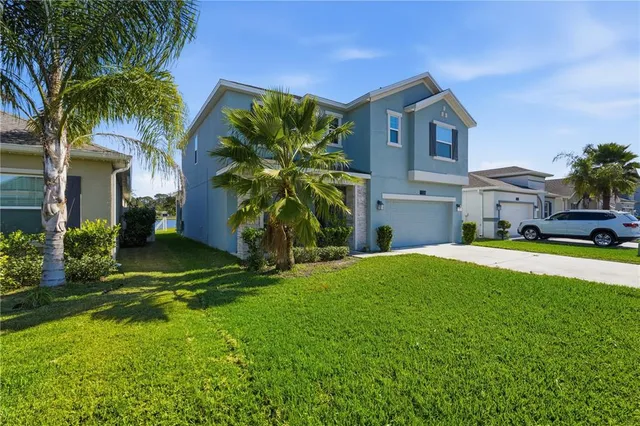 a front view of a house with a yard and palm trees