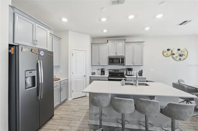 a kitchen with stainless steel appliances granite countertop a refrigerator a stove top oven a sink with island and chairs