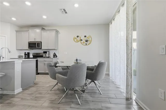 a kitchen with stainless steel appliances granite countertop a stove a sink a microwave a dining table and chairs