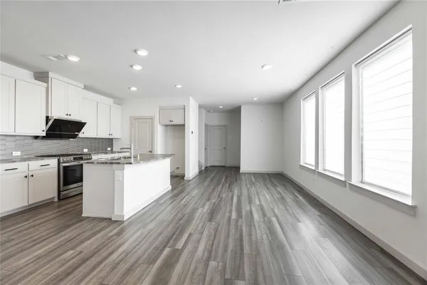 a kitchen with a sink wooden floor stainless steel appliances and cabinets