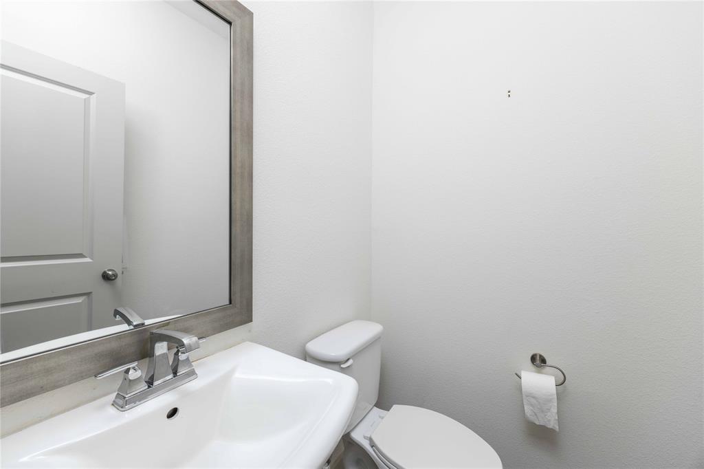 208 Spring Hill Road Flower Mound, TX 75028 - Photo 12 of 35 a bathroom with a toilet a sink and mirror