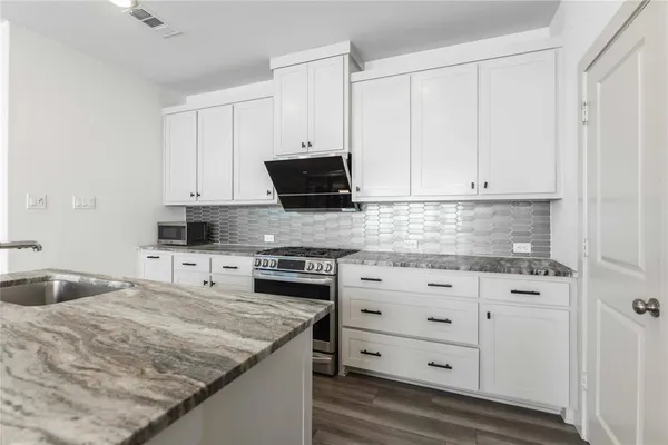 a kitchen with granite countertop white cabinets and stainless steel appliances