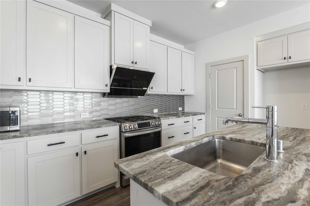 208 Spring Hill Road Flower Mound, TX 75028 - Photo 6 of 35 a kitchen with granite countertop a sink stove and cabinets