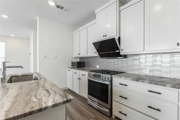 a kitchen with granite countertop white cabinets and black appliances
