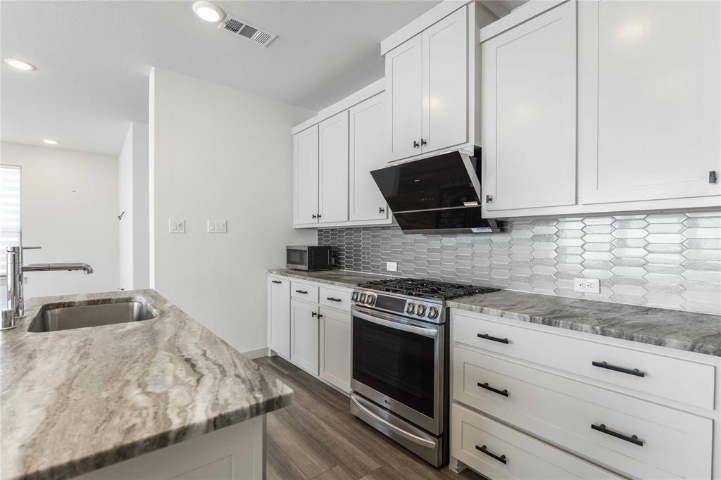 208 Spring Hill Road Flower Mound, TX 75028 - Photo 8 of 35 a kitchen with granite countertop white cabinets and black appliances
