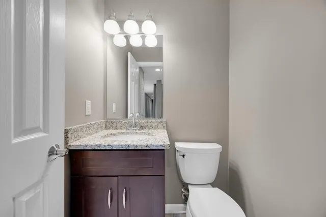 a bathroom with a granite countertop toilet sink and mirror