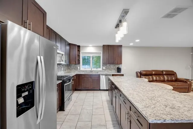 a kitchen with stainless steel appliances granite countertop a refrigerator a stove and a sink