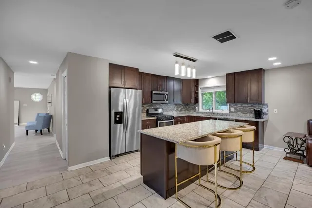 a kitchen with stainless steel appliances granite countertop a refrigerator and a stove top oven