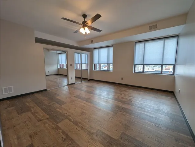 an empty room with wooden floor and windows