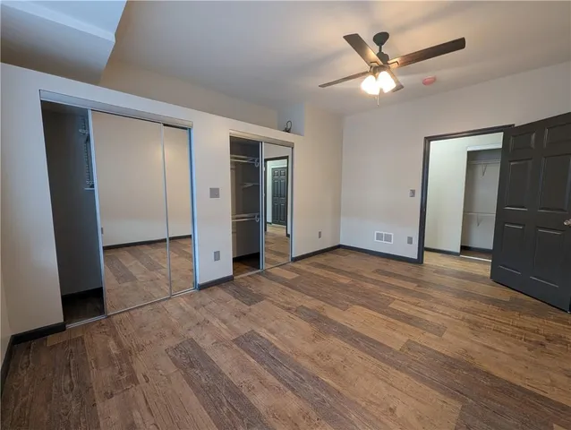 an empty room with wooden floor and a ceiling fan