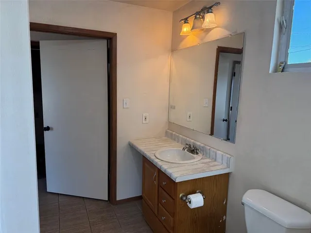 a bathroom with a granite countertop sink a toilet and a mirror