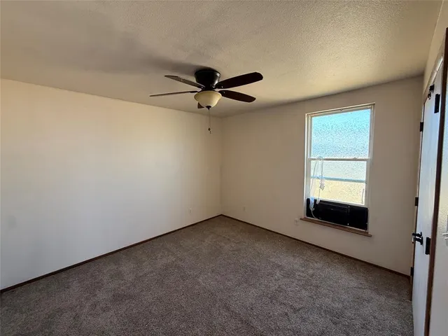 an empty room with a ceiling fan and window
