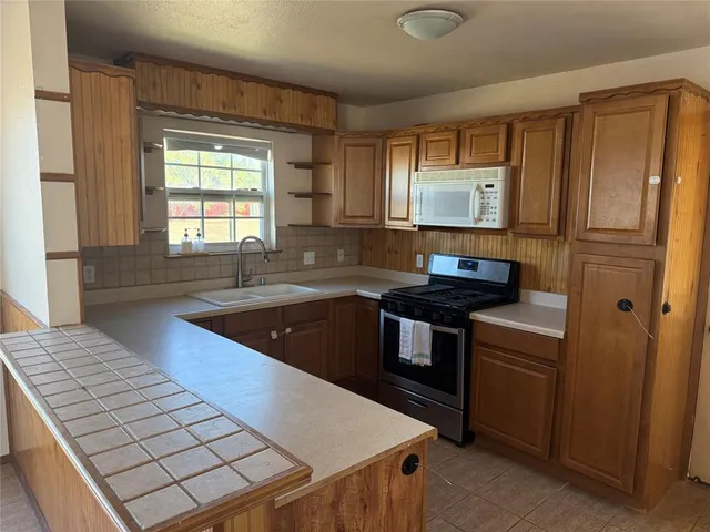 a kitchen with granite countertop a sink stove and refrigerator