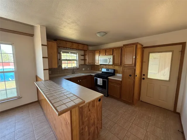 a kitchen that has a sink a stove and chairs