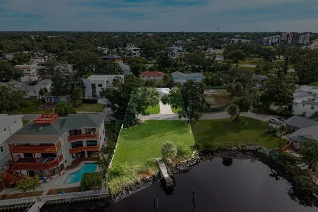 an aerial view of a house with garden space lake and trees all around