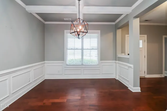 a kitchen with stainless steel appliances granite countertop a stove top oven a refrigerator a sink and a dining table with white cabinets