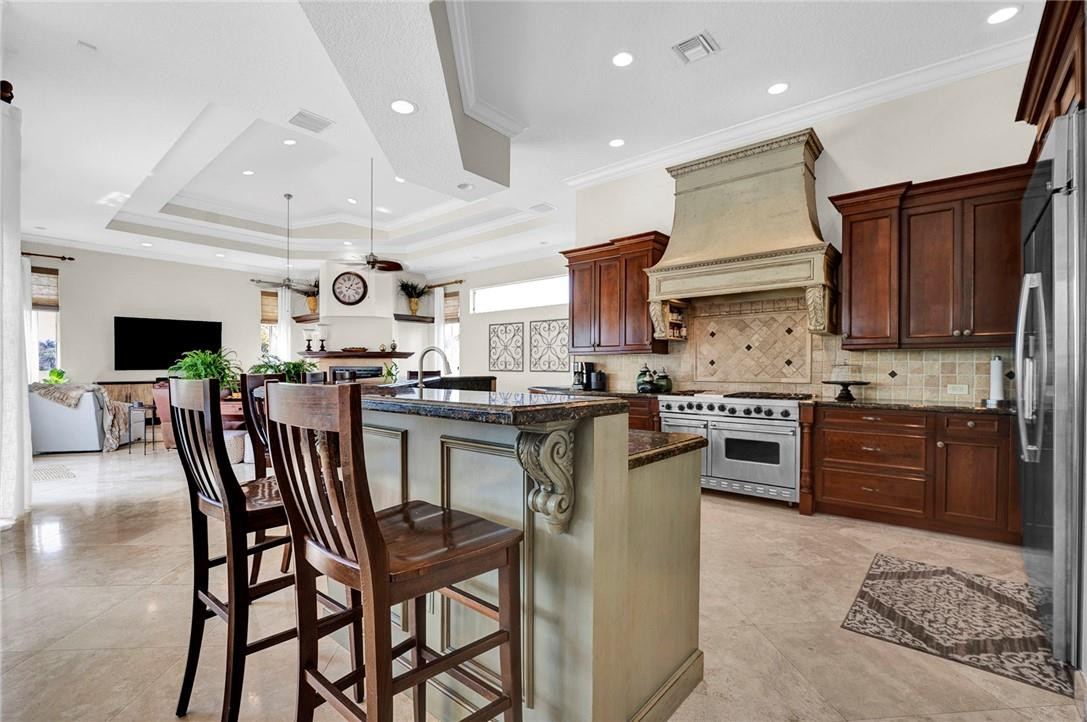 20240 Southwest 51st Court Southwest Ranches, FL 33332 - Photo 15 of 60 a kitchen with stainless steel appliances kitchen island granite countertop a stove a sink a microwave a refrigerator and chairs